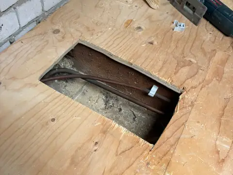Houten vloer opengezaagd voor toegang tot de onderliggende koperen leidingen