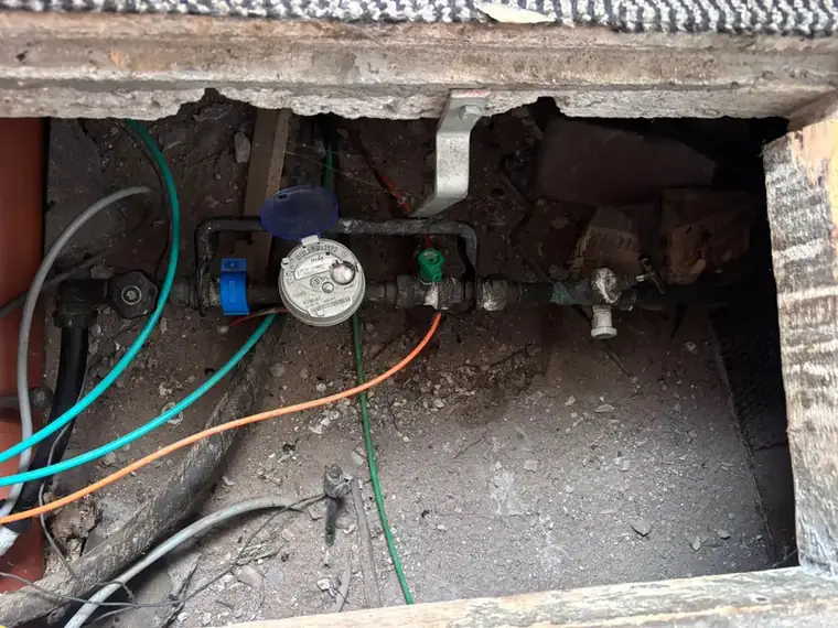 Watermeter met afsluiters in een geopende kruipruimte